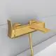 Goldfarbener Wasserhahn von Ideal Standard mit einer schlichten, modernen Form und einer Auslaufvorrichtung, montiert an einer hellen Wand.